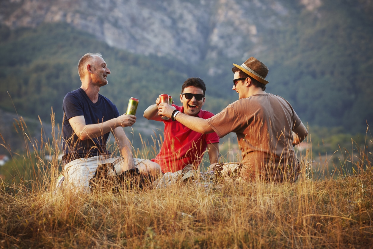 Three friends enjoying a can of beer outdoors