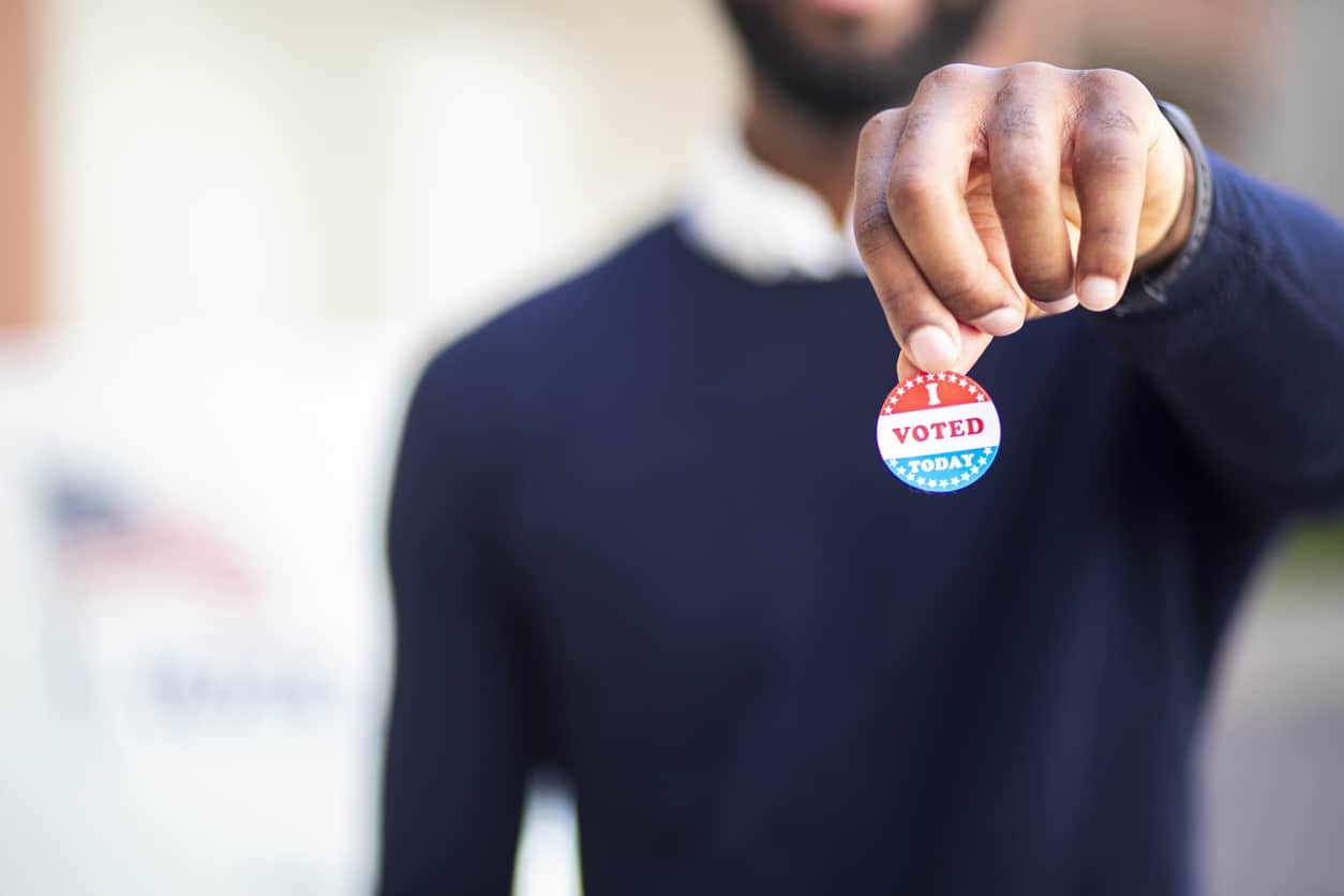 A young black man with his I voted sticker after voting in an election.